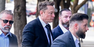 elon musk, profile, walks down the street, three body guards in suits