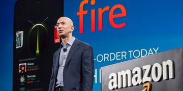 young Jeff Bezos, bald man in blue shirt and grey suit, amazon logo, fire sign in orange