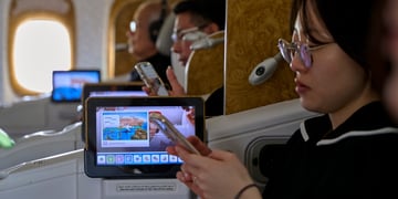 asian woman looks at her phone, black hair, tiny television screen, more passengers in the back