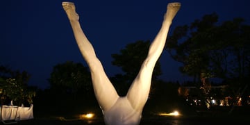 white spread legs in the dark blue night sky, warm lit sculpture