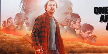 leonardo di caprio in red and white flannel shirt, shotgun, sunset, orange field, road