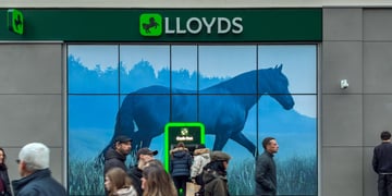 lloyds bank, green logo, people passing by, black horse logo, grey wall, warm people's outfits