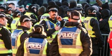 Police officers in yellow reflective rests, black hats with white squares, blue police signs