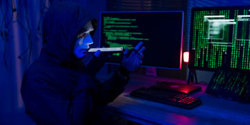 hacker, black hoody, white plastic mask on face, smartphone, two screens with green numbers, code