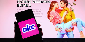 ok cupid logo, okc blue letters in white frame, pink bavkground, women kissing, red rose, screen