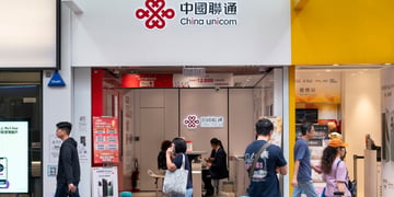china unicom written in black letter, white stand, pedestrians under, yellow wall