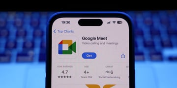 A laptop keyboard and Google Meet on App Store displayed on a phone screen