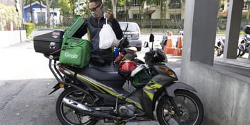 delivery driver on moped, white plastic bag, green delivery box, white GrabFood logo