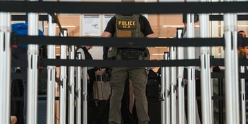 An Ice immigration agent with black security banners in front of him.