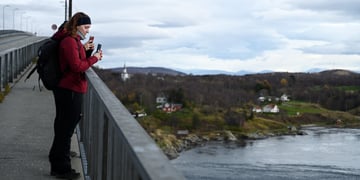 people on bridge, red jacket, maelstrom , flooded river, blue sky, white clouds, smartphone 