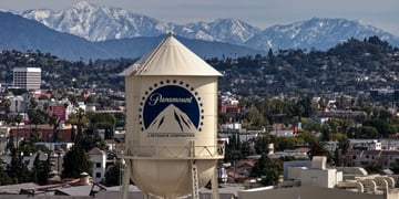 ivory water tower, blue paramount logo on it, mountains in the background, 
