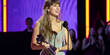 taylor swift, dark blonde almost loose hair, wavy, award statue in hand, grey-greenish strap dress