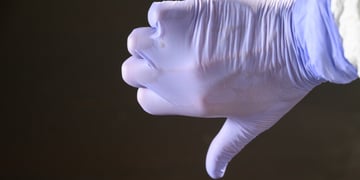 A scientist with a latex glove giving a thumbs down gesture.