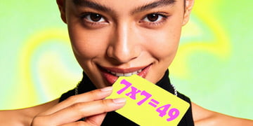 A woman holding a yellow card that has equation 7x7=49 on it