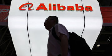 Man walks past Alibaba logo