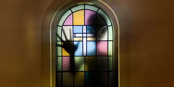 An alien silhouette pressing against a stained glass window.