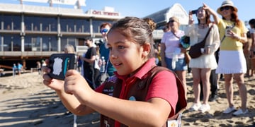 chubby girl scout, eight year old, dark pink t-shirt, vest, badges, beach, camera, people, sunny