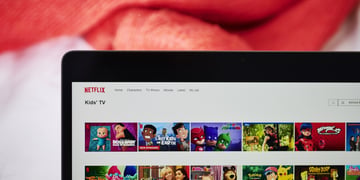 black laptop frame, white screen, netflix kids section, animated faces, red blanket