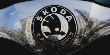 black skoda logo on a car front, reflection on buildings on silver plate, 