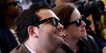 white man, chubby cheeks, dark curly hair, smiling, black ray-ban sun glasses, white woman