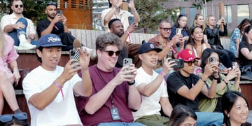 about thirty white people raising their smartphones to film, t-shirts, hats, 