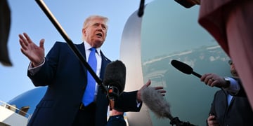 donald trump, bright blue tie, white shirt, sea blue plane turbine, black microphones, clear sky