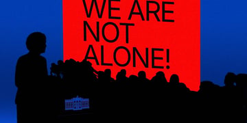 Silhouettes of journalists representing the White House with a "we are not alone" sign.