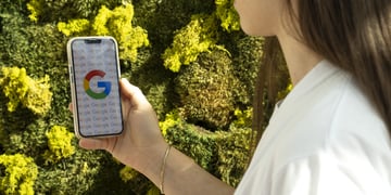 Google logo on white smartphone screen, white t-shirt, white female, long dark brown hair, green