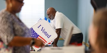 I voted sign on white paper, usa flag, black man, white shirt, black woman, black pants