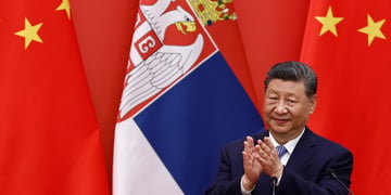 Xi Jinping, serbia flag, two china flags, black suit, white shirt, blue tie, black hair, claps, yellow stars
