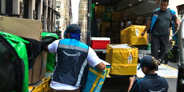 amazon prime logo, yellow plastic bags on brows cardboard boxes, two men, truck with open back