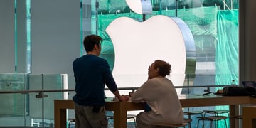 huge silver apple logo, asian man standing ,fat asian woman sitting, green background