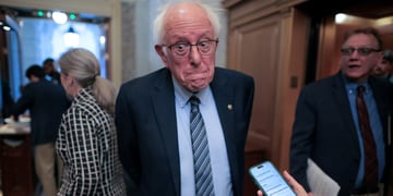 bernie sanders, white hair, band forehead, telephone, light blue shirt, glasses