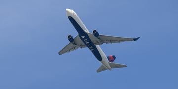 delta airline white plane in blue sky, delta sign on bottom on the plane