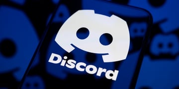 dark smartphone screen reflects one big white discord logo, little darker ones are in the back