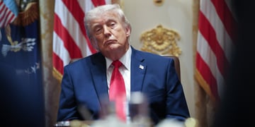 donald trump, two US flags, one flag pin in dark blue suit, white collar shirt, red tie, blonde hair