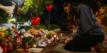 flowers, red heart balloons, woman on her knees praying on street, dark evening, long black hair