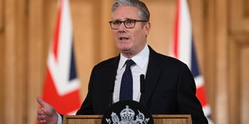 keir starmer, black suit, two UK flags, dark tie, white collar shirt, 