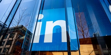 LinkedIn logo behind glass wall of a huge building, reflection of the cityscape