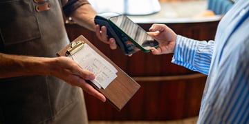 Person paying the bill by card while server holds the card reader