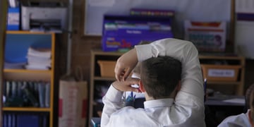 white male school boy in classroom, white collar shirt, right hand over head, light hair
