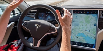 white man hands, black tesla wheel, screen with map on it, car front window, bright red shirt
