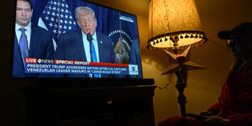 warm light floor lamp, donald trump on big tv screen, dark room, blue tie, white collar shirt