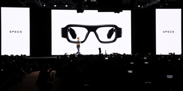 three huge white screens, black glasses, spiegel, white male in stage, black frames