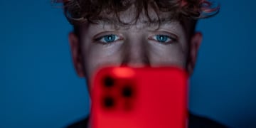 teen boy, curly hair, red smartphone, dark blue room, blue eyes