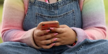 pink nails, smartphone, jeans, rainbow color top