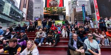 people sitting on stairs, time square, coca cola red billboard, tall glass buildings