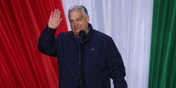 victor orban waves right hand, hungarian flag color curtain, red, white, green, black jacket, grey hair