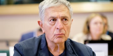 Stelios Kouloglou, white elder greek man, black collar shirt, no tie, grey hair, dark blazer,
