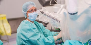 female doctor, light blue face mask and hair net, light mint scrubs, glasses, operating room, 